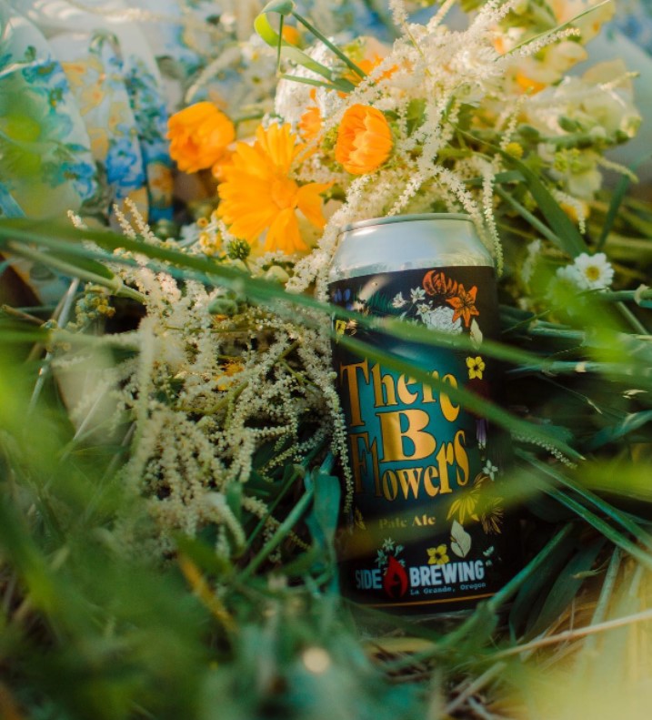 can of beer nestled in grass and wild flowers