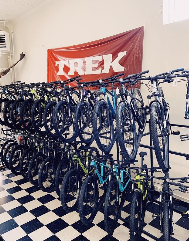 bikes on display in two rows in bike shop with checkered flooring and banner for TREK