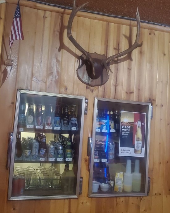 wood paneled wall with coolers built in and mounted deer antlers above