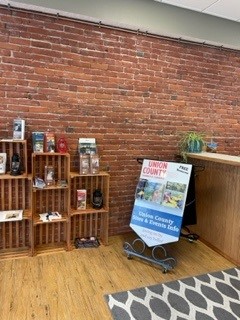 interior of information center with wood floors, brick wall and displays of brochures on shelves