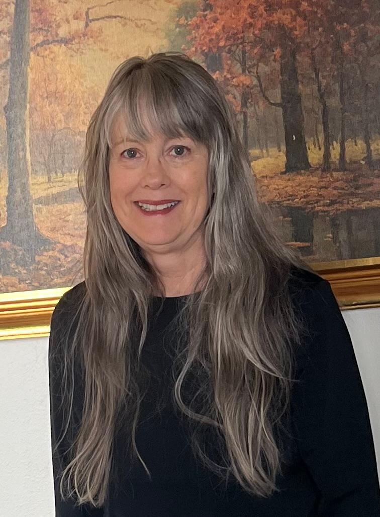 Angie Thomas standing in front of forest painting