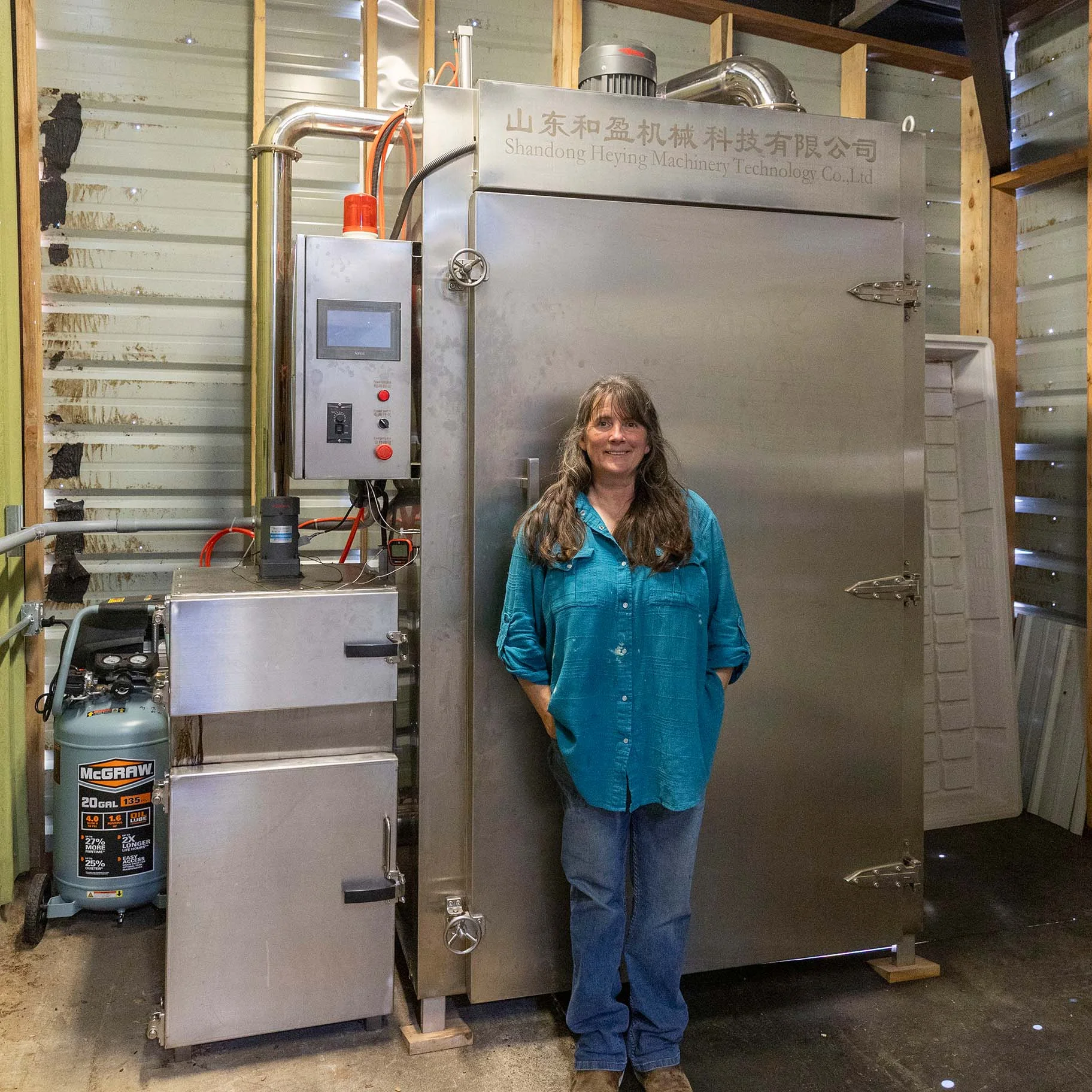 Little Fine Fine Seafood Market Co-Owner Greta Horn standing in front of their smoker.JPG