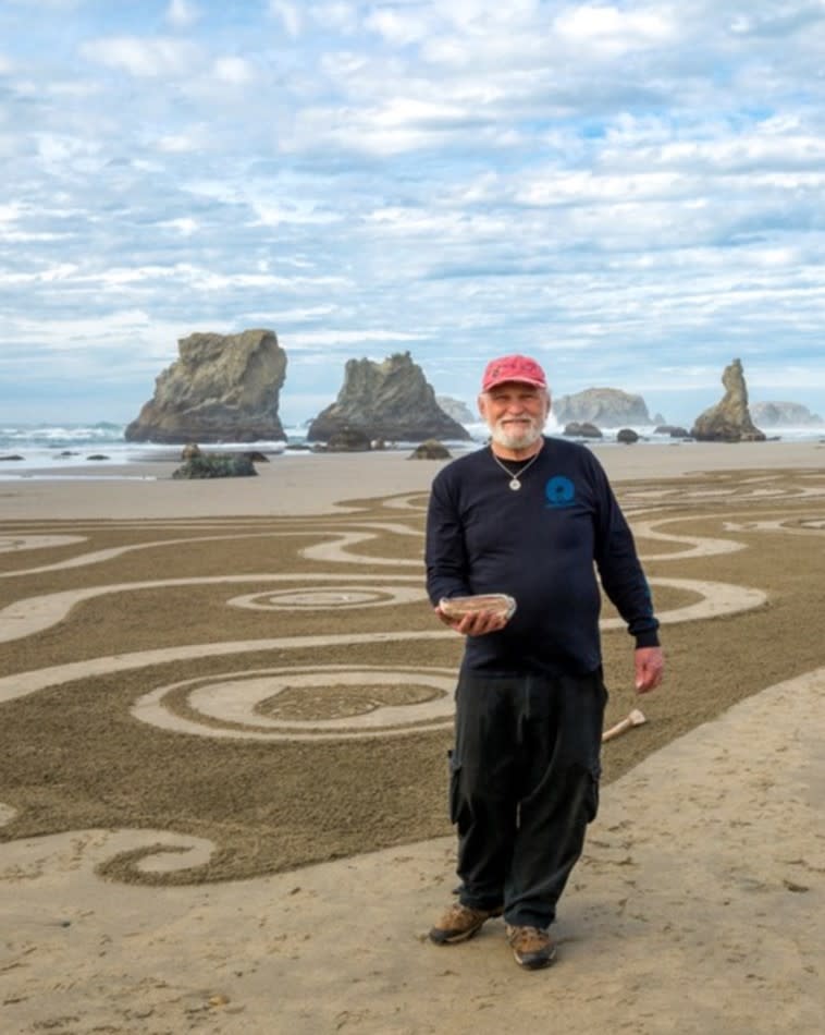 Denny Dyke sand artist posing next to Circles in the Sand beach art with ocean in the distance