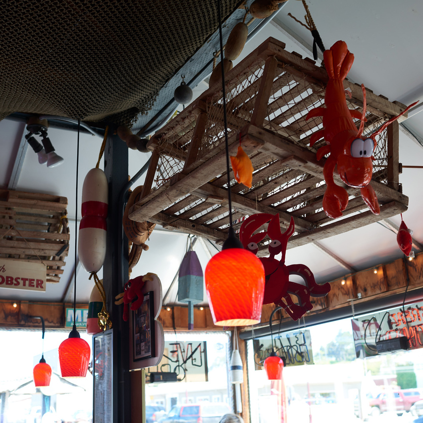 pendant lights, wooden crab trap and inflatable toy lobster hang from ceiling of restaurant