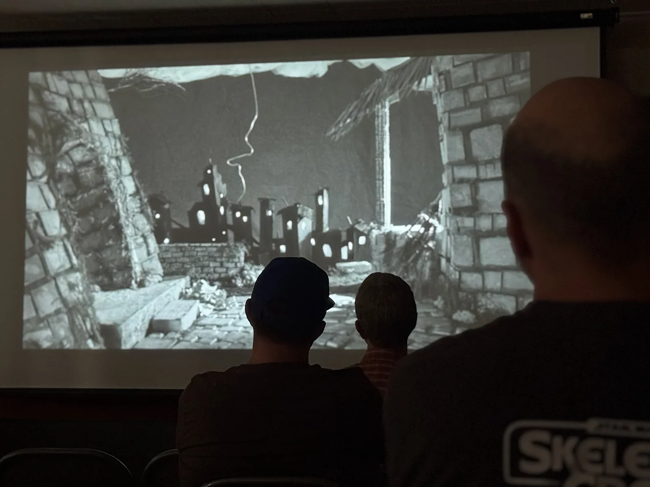 Silhouettes of people watching animated film in dark room