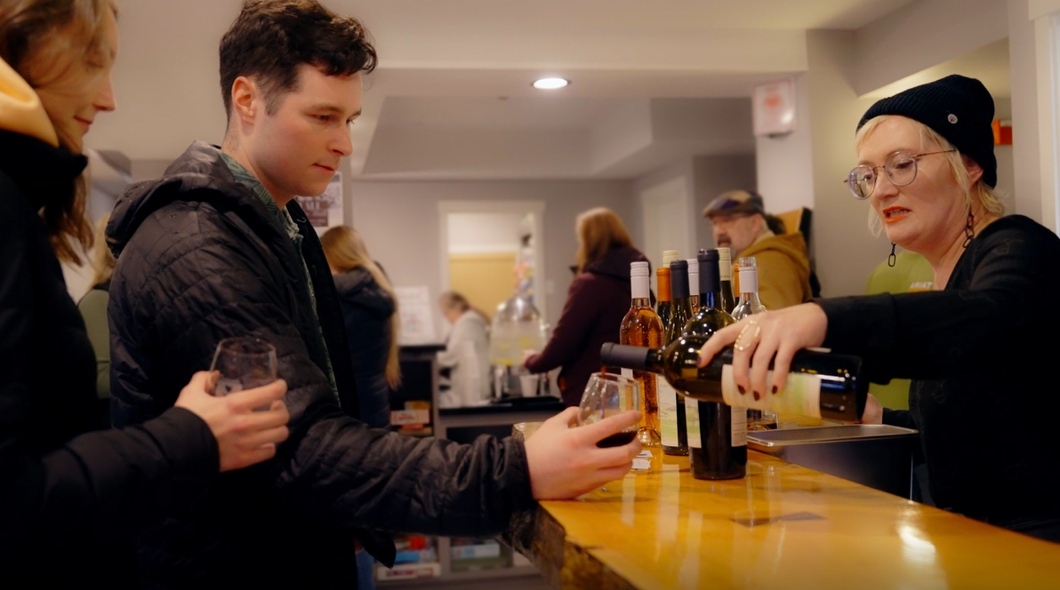 Woman pouring wine for couple at Downtown Fall Wine Walk wine tasting