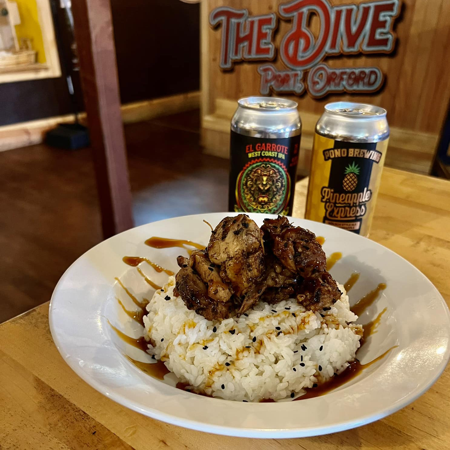 plate of Teriyaki Chicken sitting next to two cans of beer