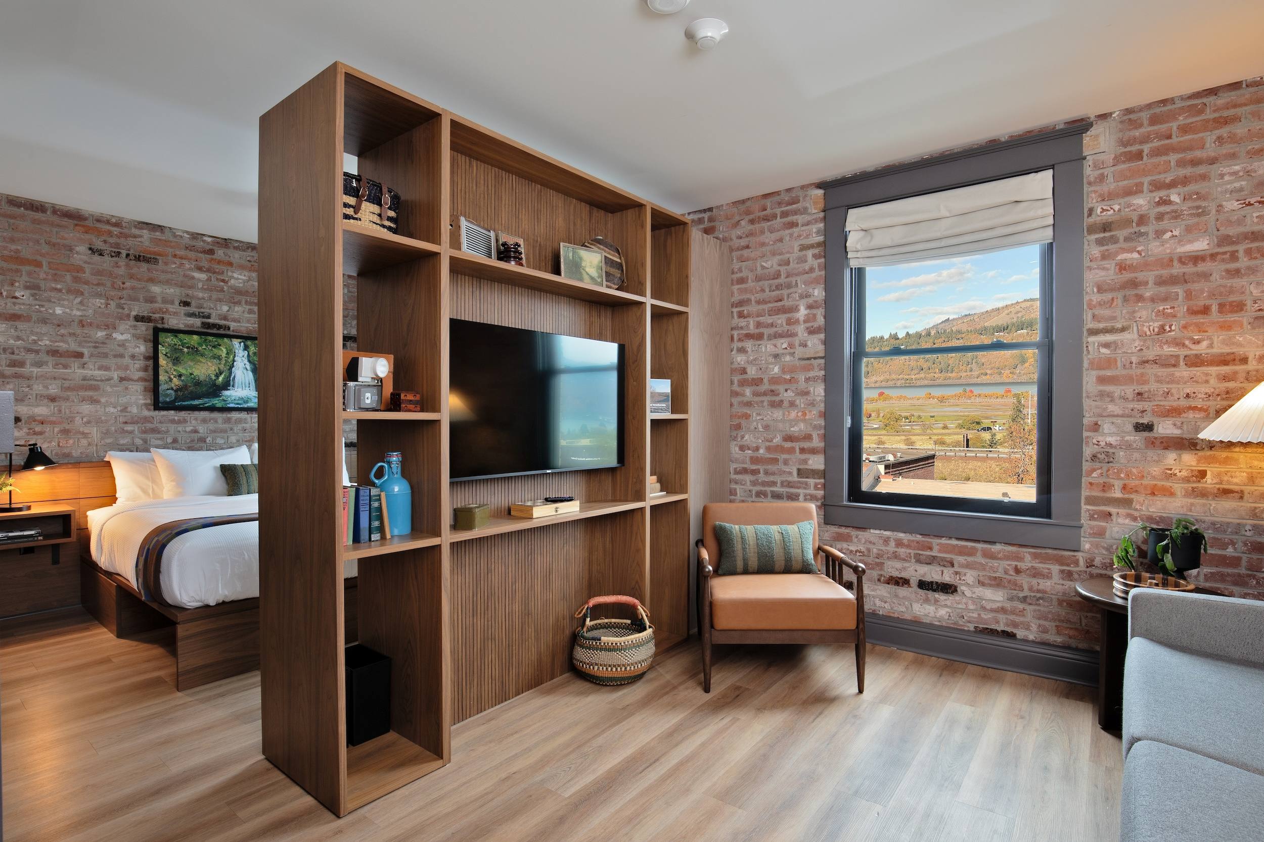 Hotel suite with brick walls and shelf dividing the bedroom from sitting room.