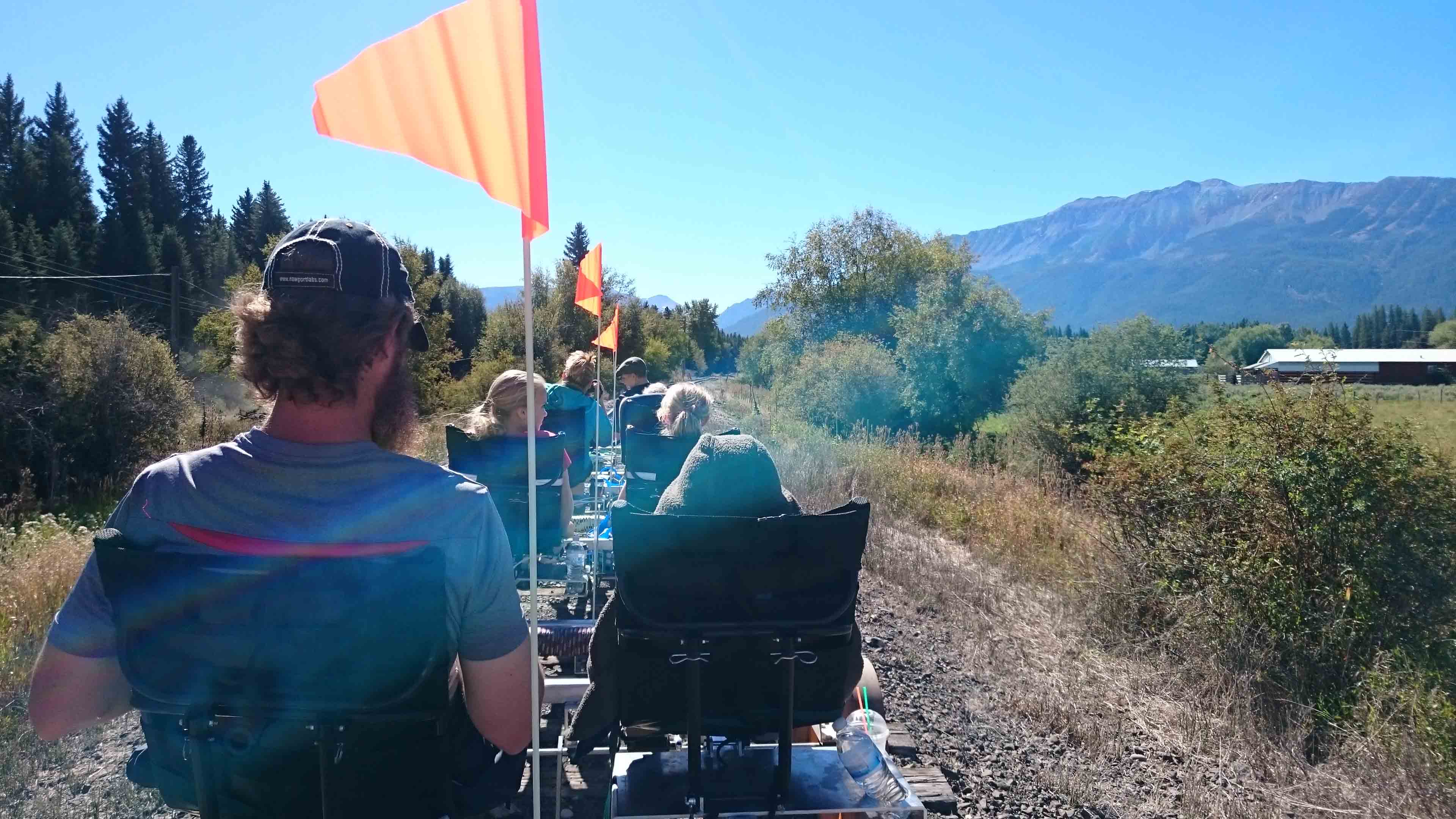 group of people riding on recumbent quadracycles on railroad tracks through scenic landscape