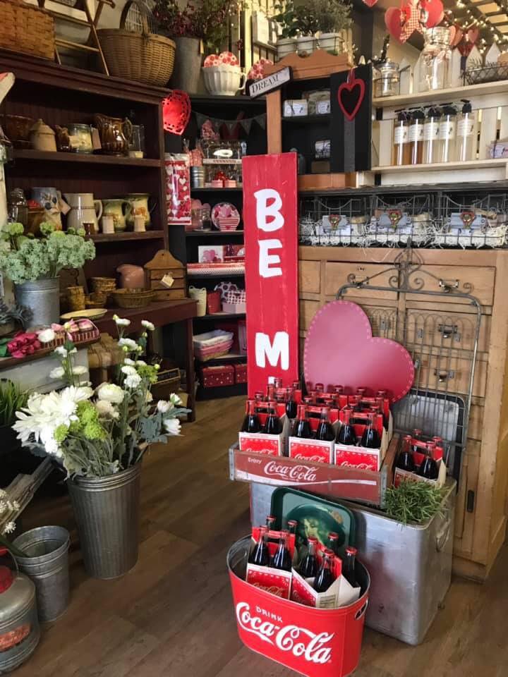 interior of retail shop with displays of fresh cut flowers, six packs of Coca-Cola bottles and home goods