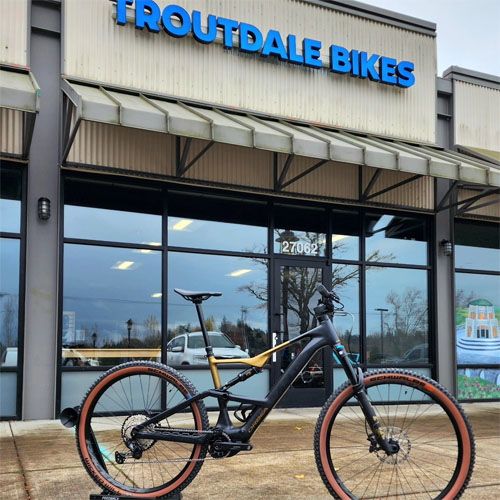 A black Orbea bike stands in front of the Troutdale Bikes storefront