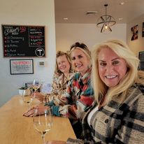 Three women at the bar with wine glasses dressed for cold weather