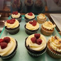 Six  raspberry topped cupcakes and three nut topped cupcakes on a tray