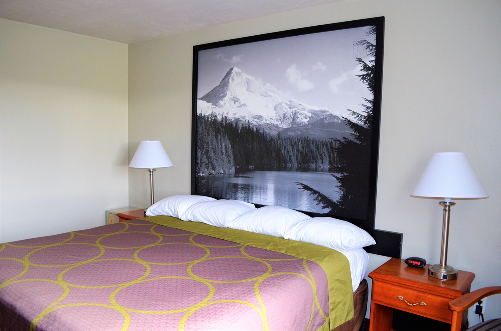 Bedroom with king size bed, lamps and picture of mountain on the wall