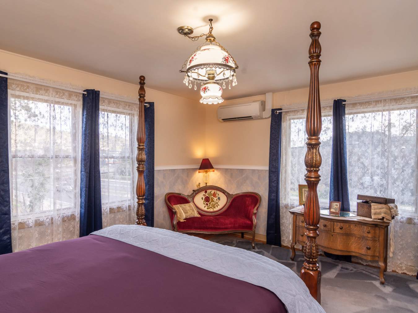 Clara's room with blue drapes, red setee, tall wooden bedposts.