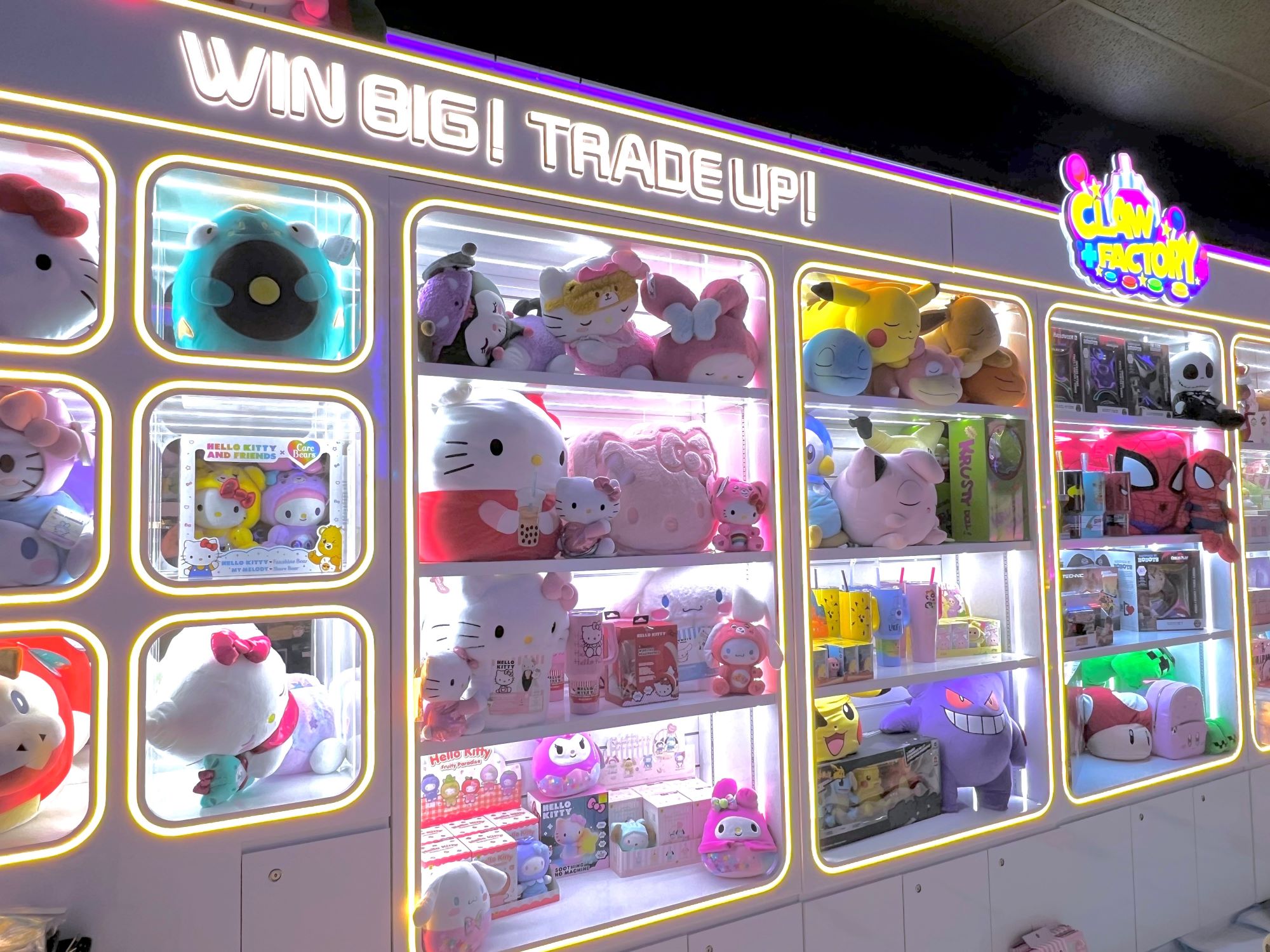 A wall of cubbies full of stiffues backlit with a sign that says Win Big, Trade Up