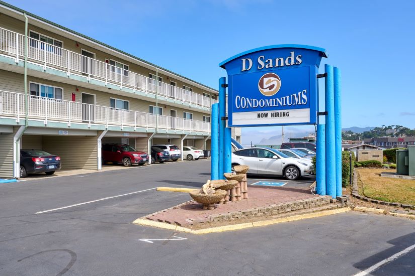 exterior of two story motel with blue skies and blue sign