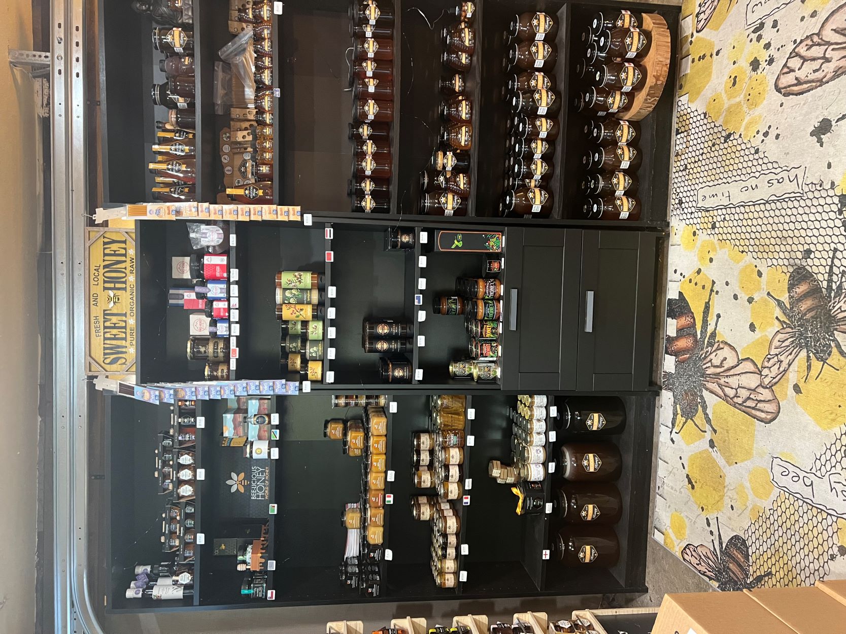 black shelving unit full of honey in various sized and shaped bottles