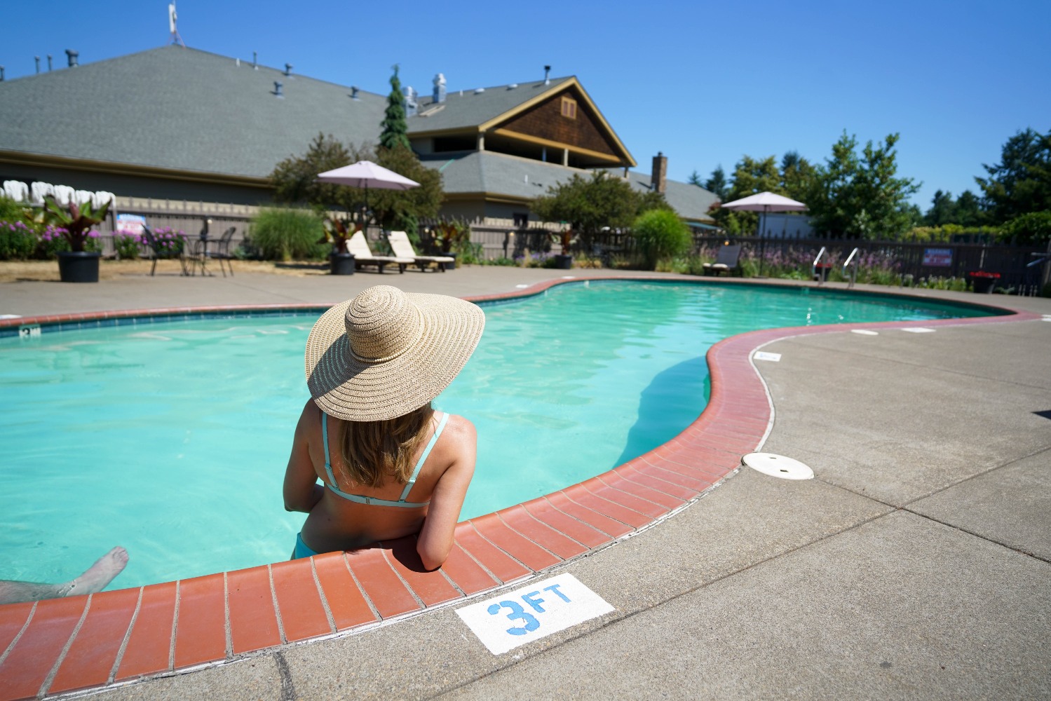outside pool with a woman wearing a sun hat looking back at the Oregon Garden Resort