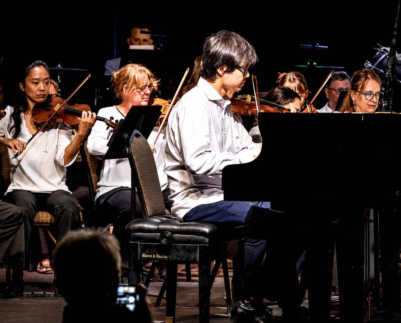 A group of musicians play violins and piano