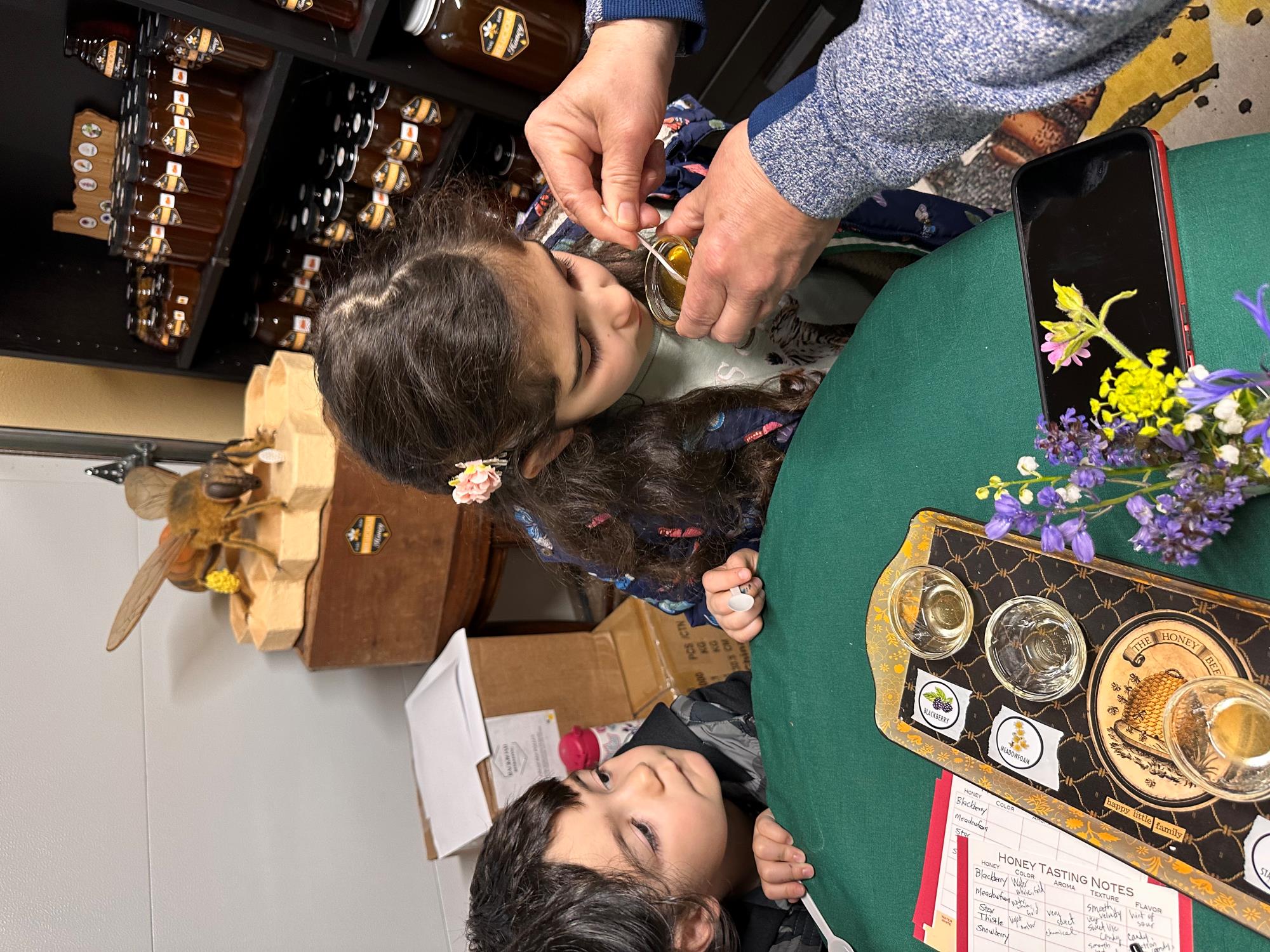 two young children taste honey
