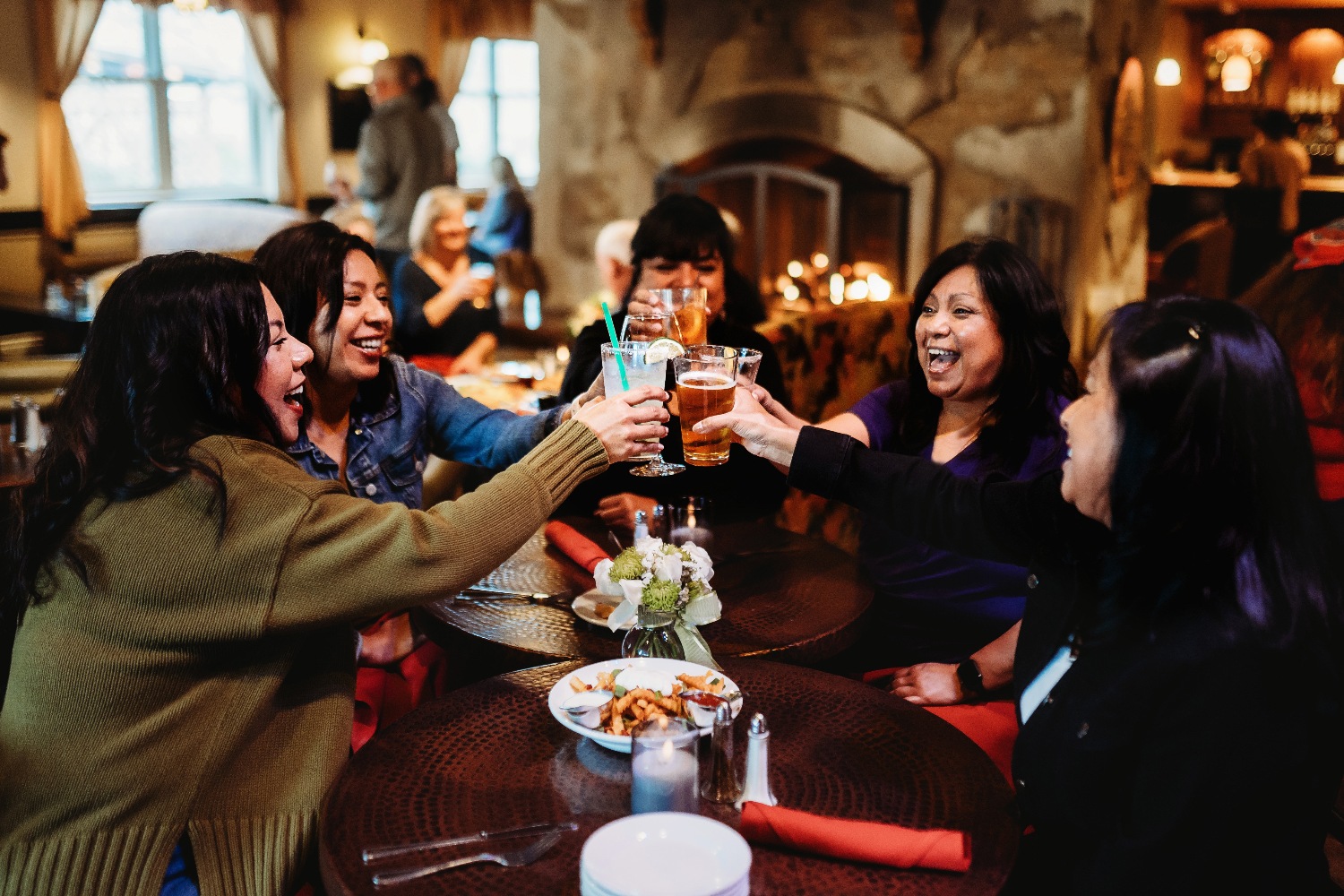 group of women holding drinking glasses up in celebration