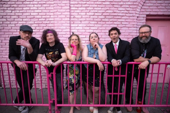 6 band members from Blonde Neon stand in front of a pink wall