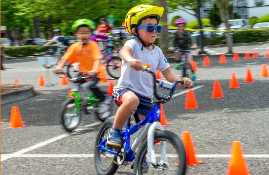 kids in colorful clothing riding bikes around orange traffic cones