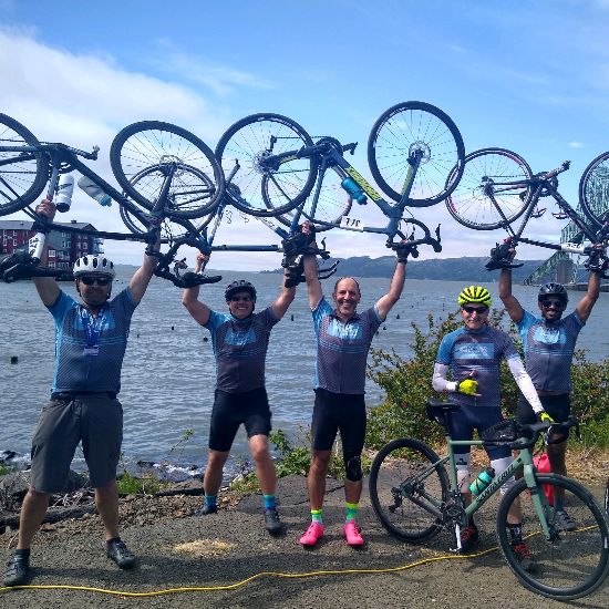 Bicyclists holding bikes over hteir heads after completing bike race