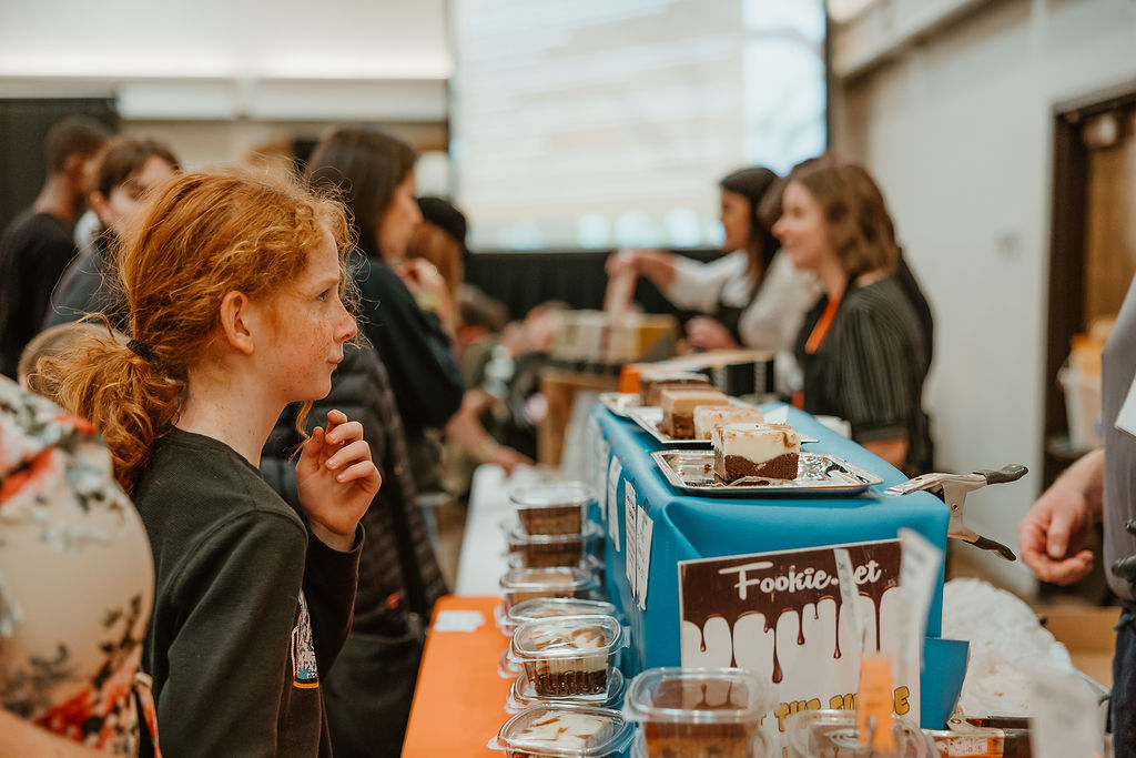 A young woman with red hair tastes a piece of chocolate at a chocolate festival