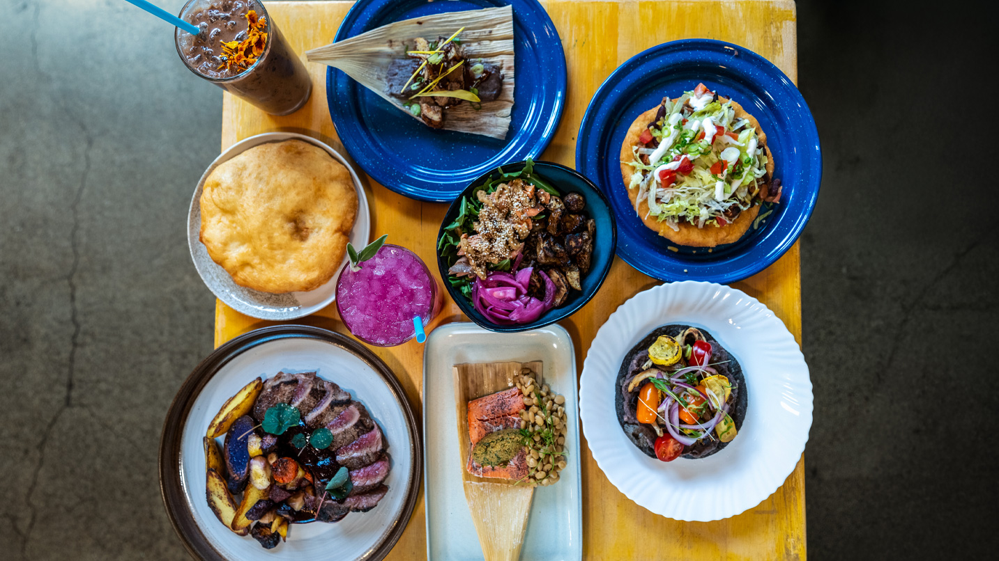 A tablescape with various blue and white plates filled with colorful native foods