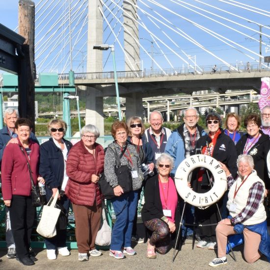 group of people smiling outside in front of Tilikum Bridge