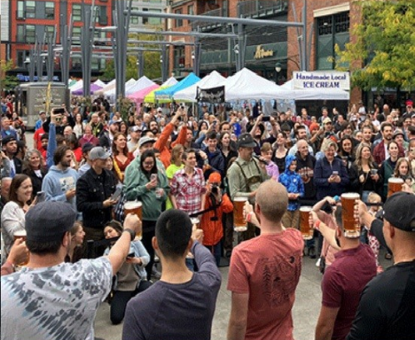 large crowd of people at festival holding beer steins
