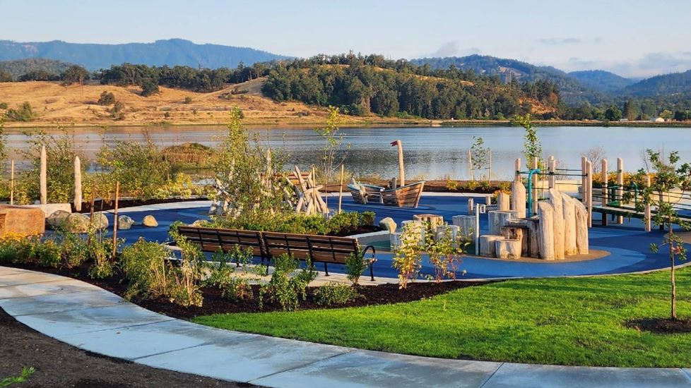 inclusive playground with natural materials play structures and lake in background