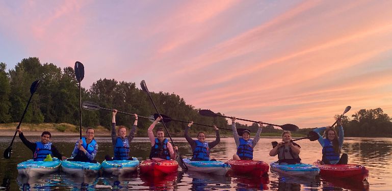 group of kayaker smiling on the river during sunset