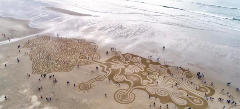 aerial view of ocean beach with sand labyrinth and people
