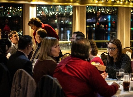 people enjoying a meal on a cruise ship with holiday lights twinkling