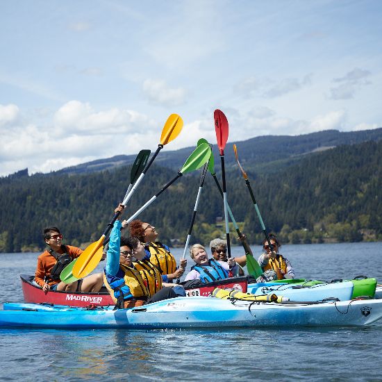group of kayakers on the water holding oars in the air
