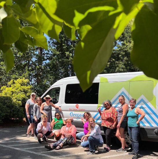 group of people in smiling in front of tour van