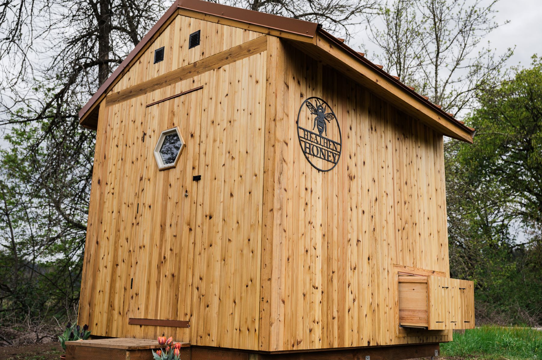 A small cedar building with a sign that says Heathen Honey