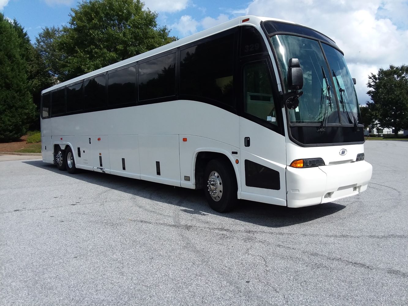 white charter bus on parking lot with blue skies