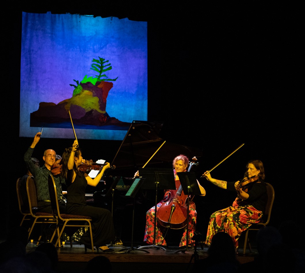 A small group of musicians play stringed instruments on a stage