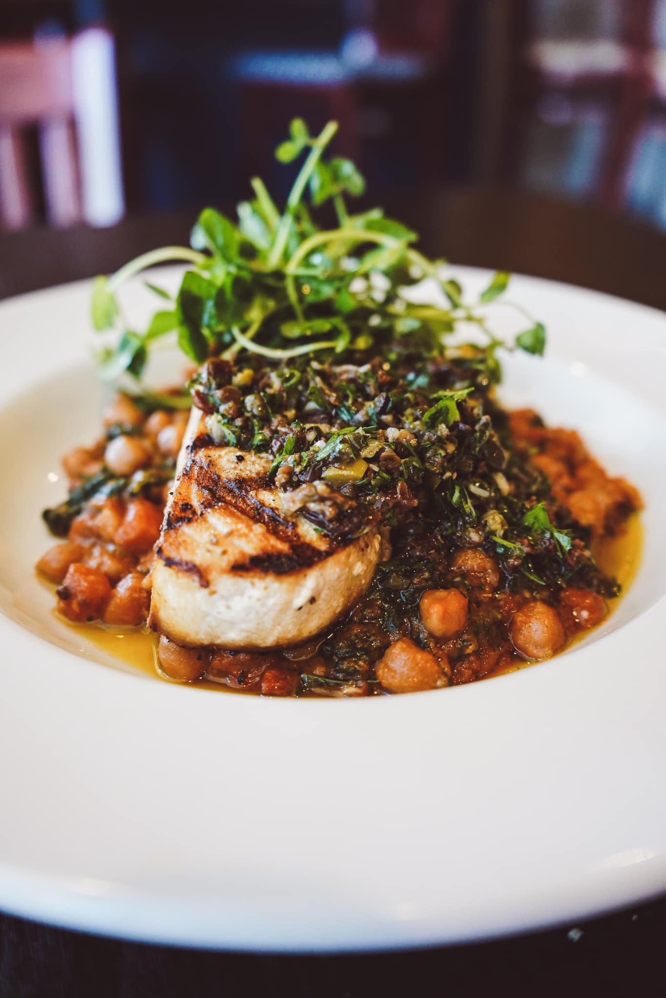 entree plate of roast chicken and chickpeas with micro greens