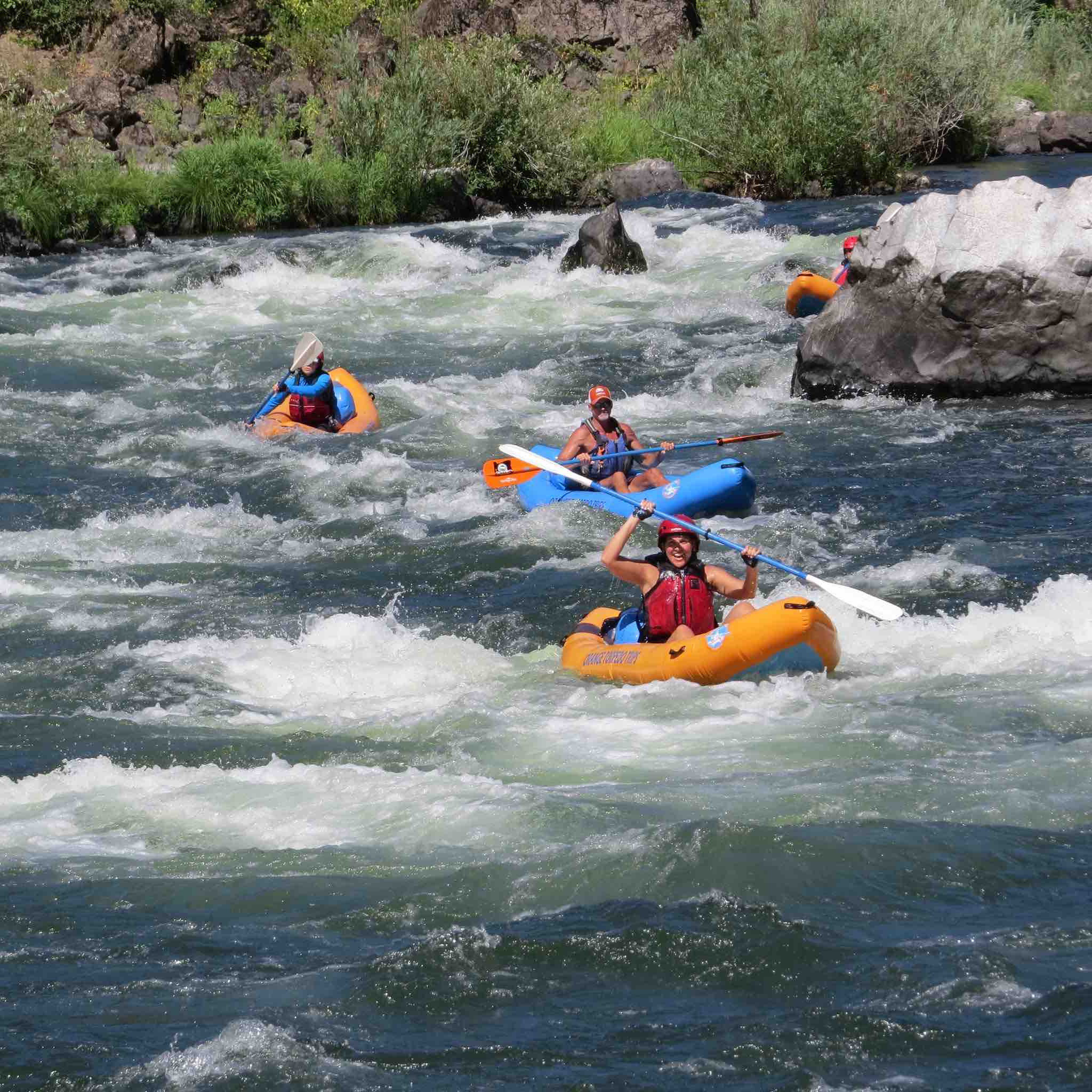 three kayaks paddle in rapids