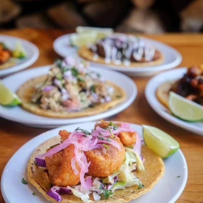 four different flavored tacos on individual plates