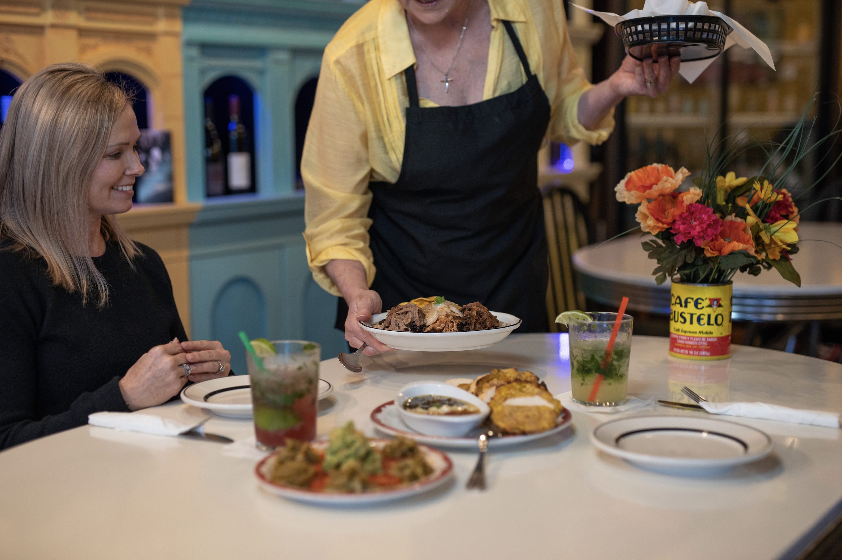 Server is setting down an assortment of cuban food