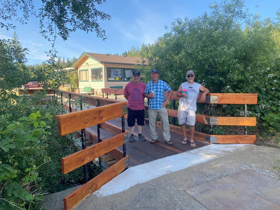 three men post on wooden bridge