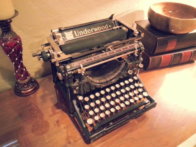vintage Underwood typewriter sits atop a desk next two two textbooks