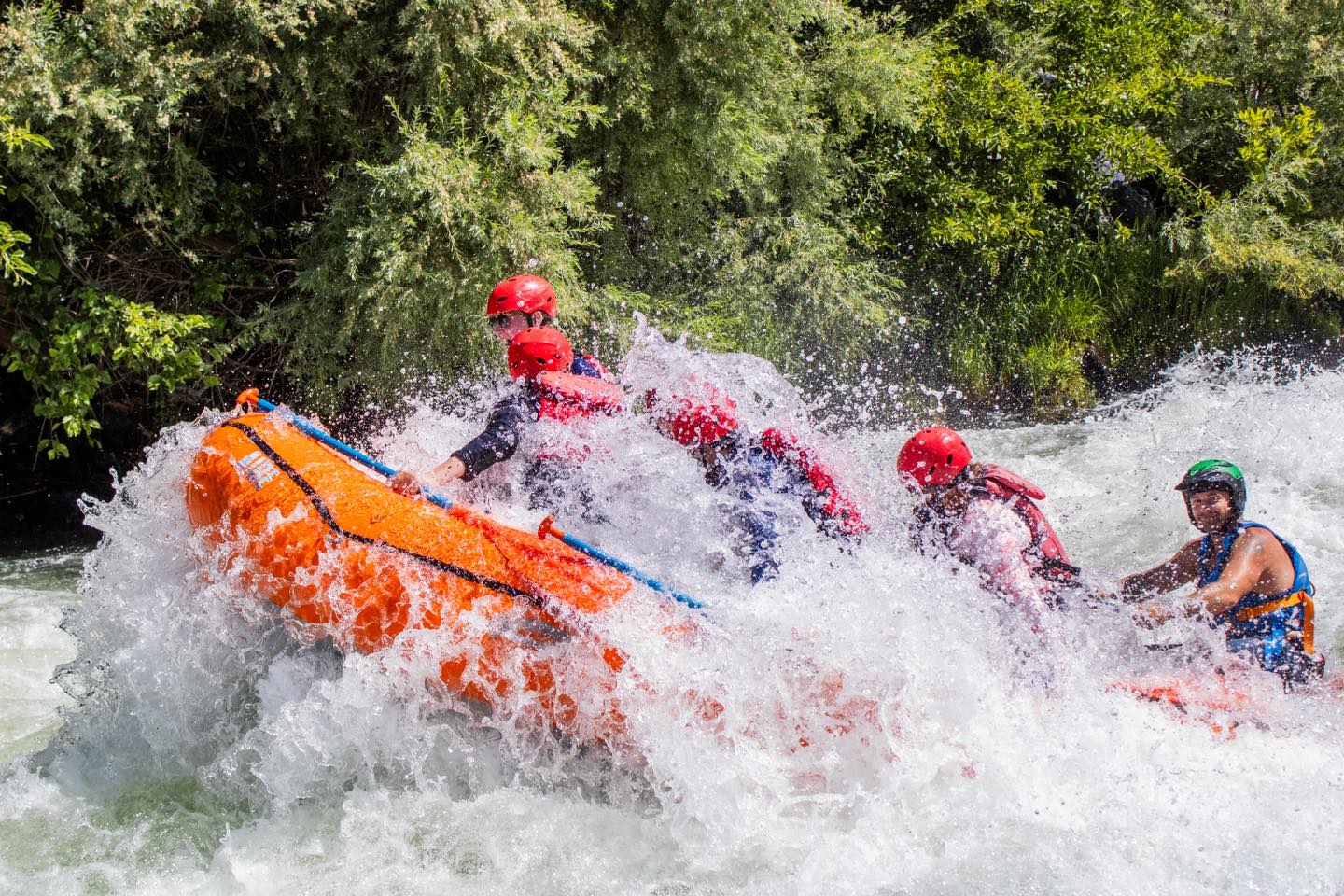 raft of kayakers splashes in rapids