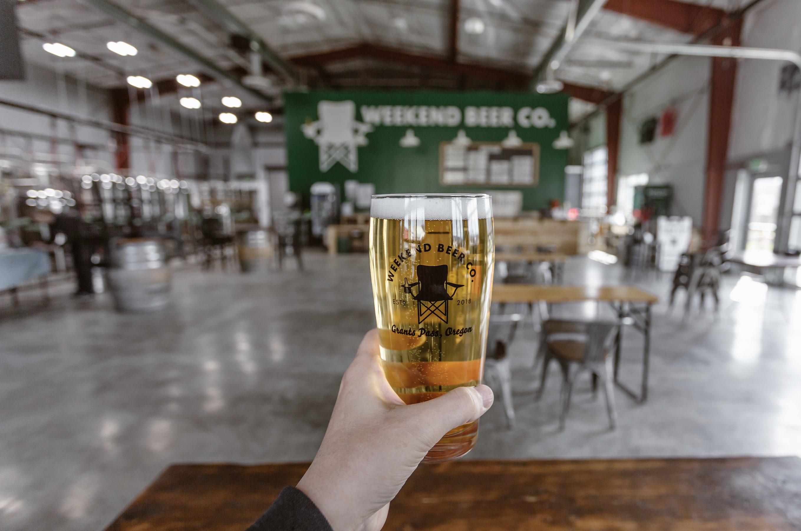 Weekend Beer Company pint glass with the company logo, a lawn chair with a beer